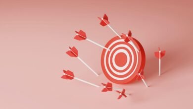 Red and white target with several arrows missing the bullseye on a pink background.