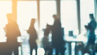 Silhouettes of people in a modern office with bright sunlight streaming through windows.