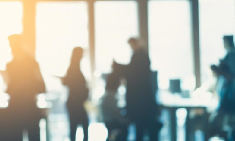Silhouettes of people in a modern office with bright sunlight streaming through windows.