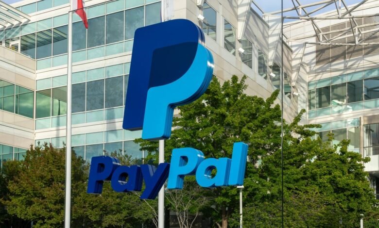 Large blue PayPal logo and text in front of a modern glass-fronted building.