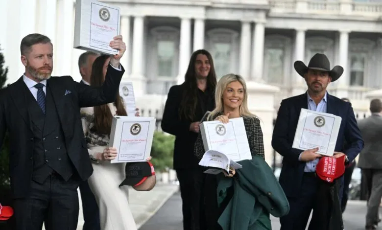 Group of people holding binders outside a building with columns, some wearing hats.