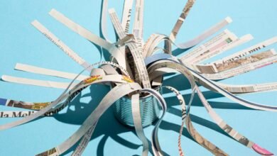 Shredded newspaper strips emerging from a tin can against a blue background.