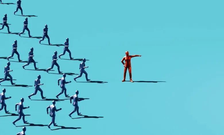 A single red figure points the way for a crowd of blue figures running in unison.