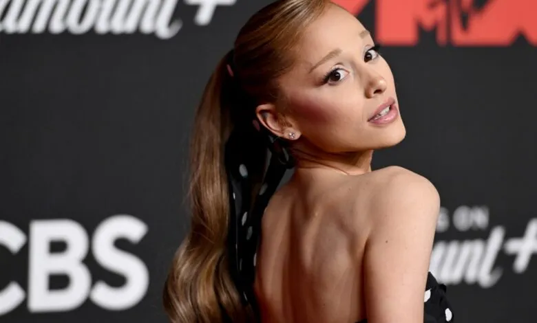 Ariana Grande poses for a photo, looking over her shoulder with a smile.