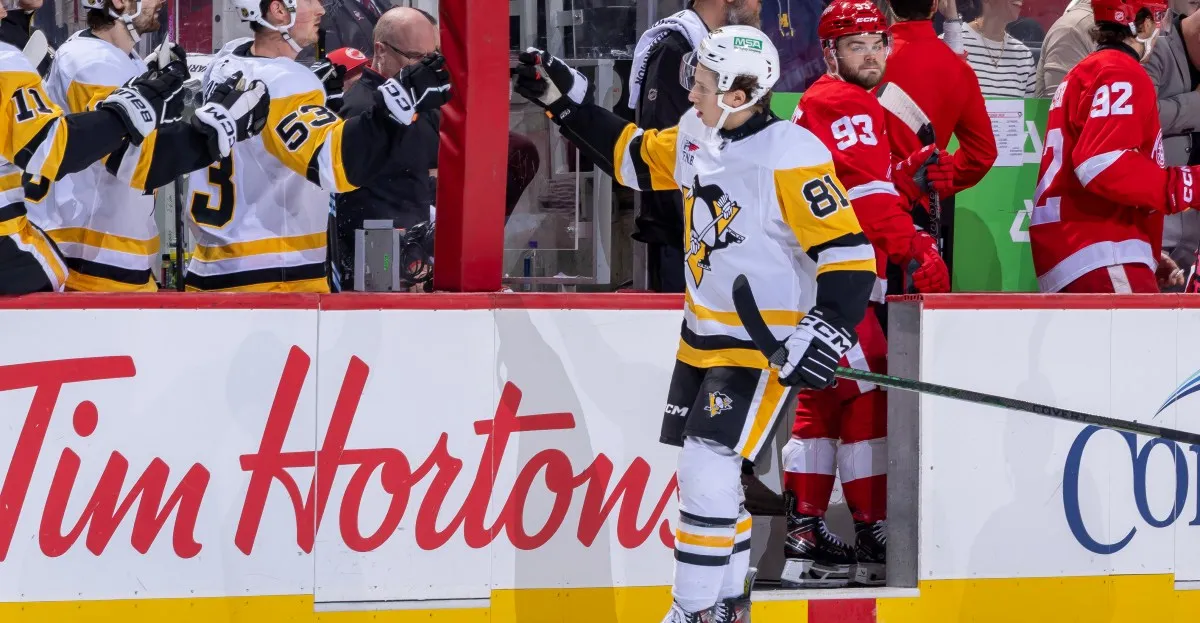 Pittsburgh Penguins player #81 celebrates on the ice with teammates and opponents in the background.
