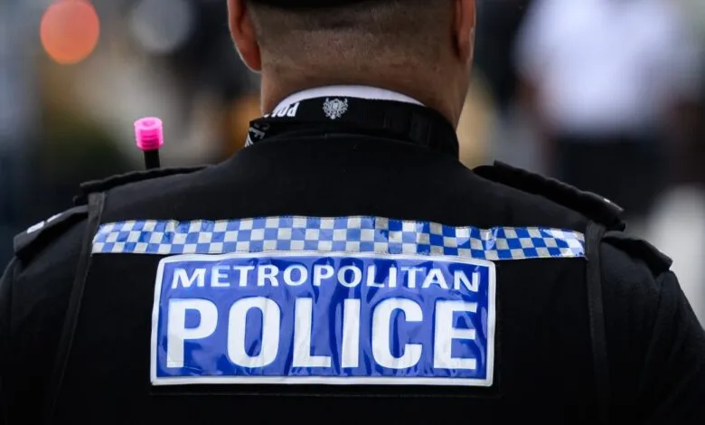 Close-up of a Metropolitan Police officer's uniform showing the 'POLICE' badge.