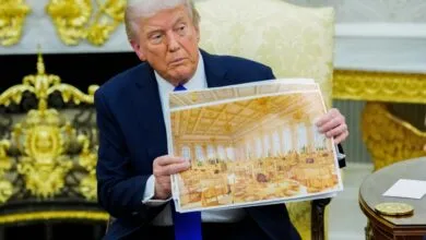 Donald Trump holds up a photograph of a grand ballroom set for a formal event.