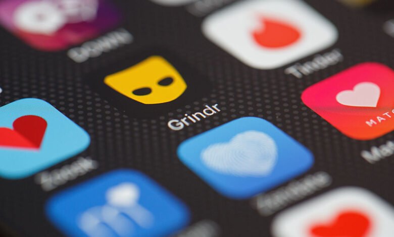 Close-up of a smartphone screen showing various dating app icons, including Grindr and Tinder.