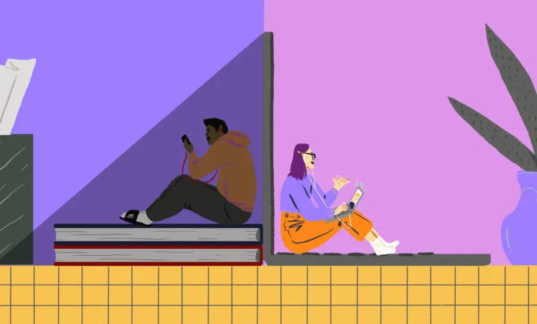 Two people sitting apart, one on books with a phone, the other on a laptop.