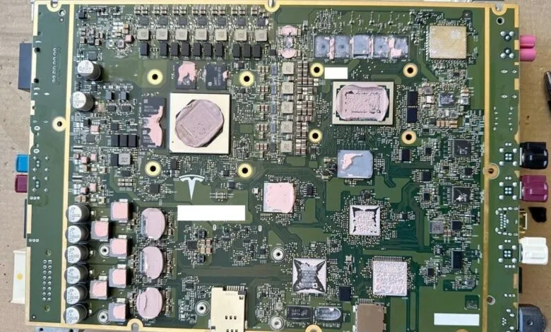 Close-up view of a complex Tesla automotive circuit board with visible chips and connectors.