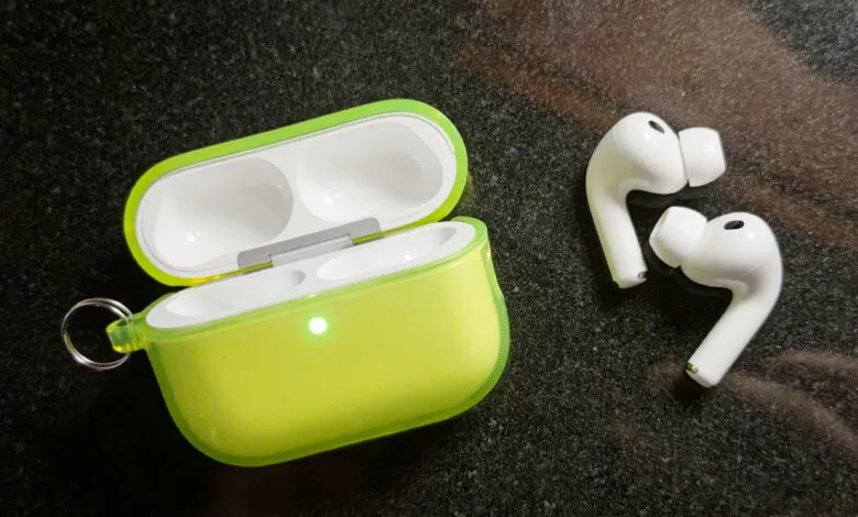 White wireless earbuds and their open neon green charging case on a dark speckled surface.