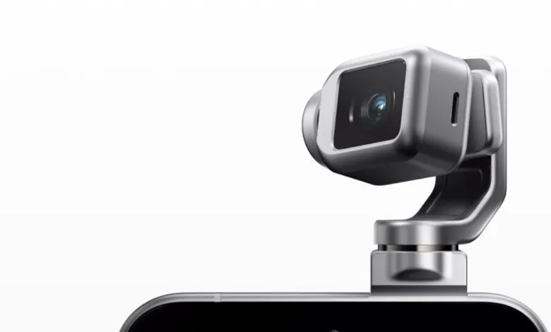 Close-up of a sleek, silver robotic camera mounted on a smartphone.