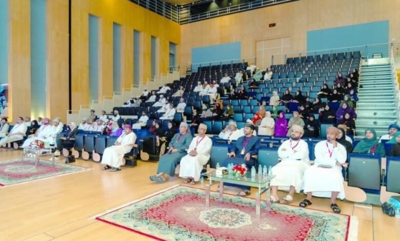 Audience seated in a modern auditorium with tiered seating and wooden accents.