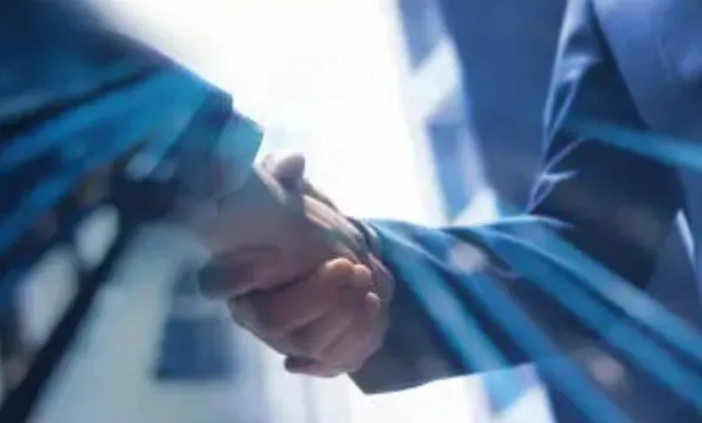 Close-up of two business professionals shaking hands, symbolizing partnership and agreement.