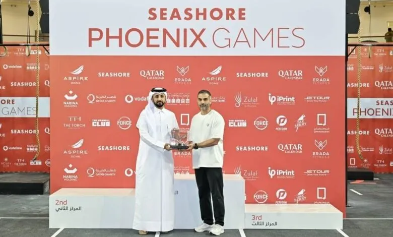 Two men holding a trophy on a podium at the Seashore Phoenix Games awards ceremony.