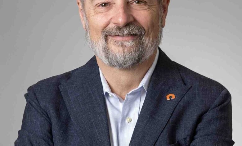 Man with a beard and flat cap smiling with arms crossed