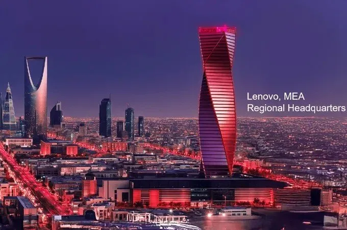 Twisted skyscraper lit red at night in a city skyline with other buildings and lights.