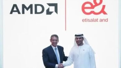 Two men shaking hands in front of AMD and Etisalat logos.
