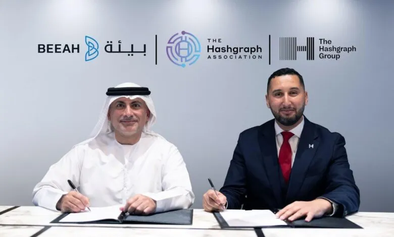 Two men in business attire signing a document, with company logos in the background.