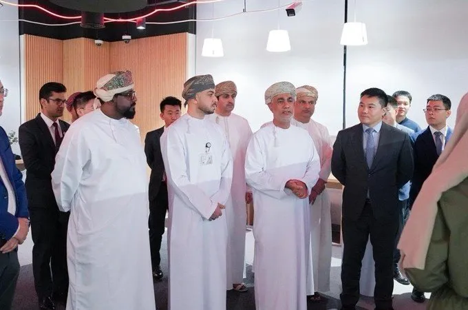 Group of men in traditional Omani attire and business suits in a modern office setting.