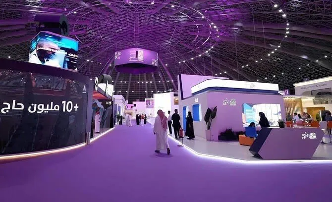 Modern exhibition hall with purple lighting, featuring digital displays and white booths.