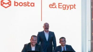 Three men in suits posing in front of Bosta and e& Egypt logos.