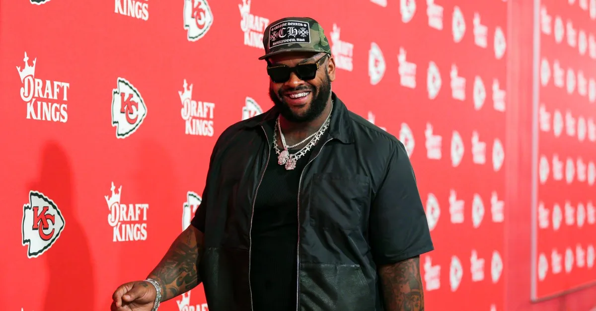 NFL player Chris Jones smiles on a red carpet with DraftKings and Kansas City Chiefs logos.