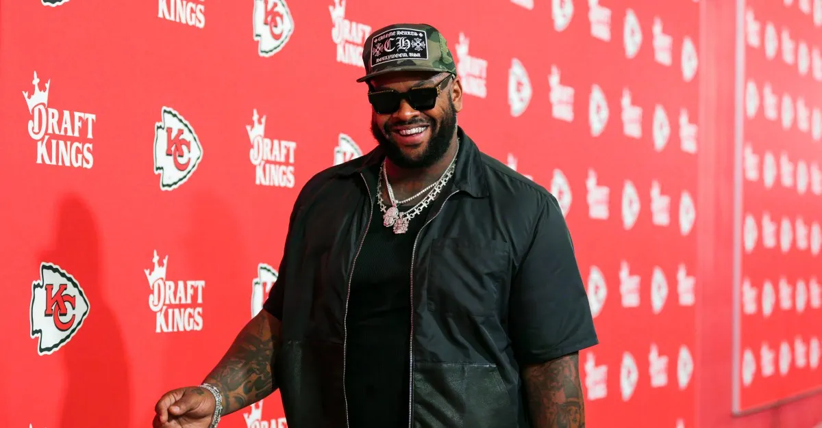 NFL player Chris Jones smiles on a red carpet with DraftKings and Kansas City Chiefs logos.