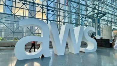 Large white AWS logo letters in a modern building lobby with glass architecture.