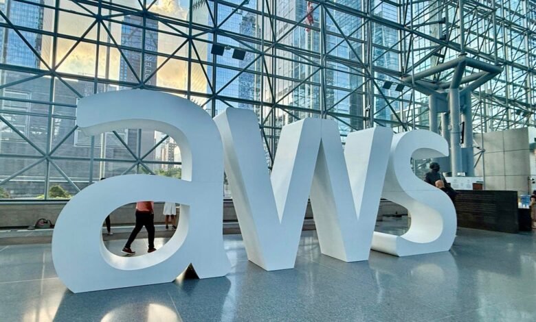 Large white AWS logo letters in a modern building lobby with glass architecture.