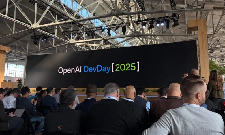 Audience watches a large screen displaying "OpenAI DevDay [2025]" at a conference.