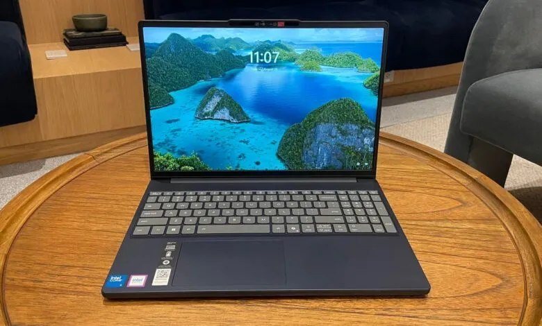 A modern laptop with a tropical island wallpaper is open on a wooden table.