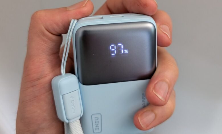 Hand holding a light blue power bank displaying 97% battery charge.