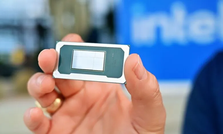 Close-up of a hand holding an Intel processor with a grid pattern on its surface.