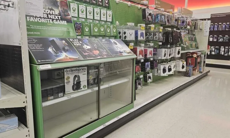 Retail display of Xbox gaming accessories, including controllers, headsets, and game passes.