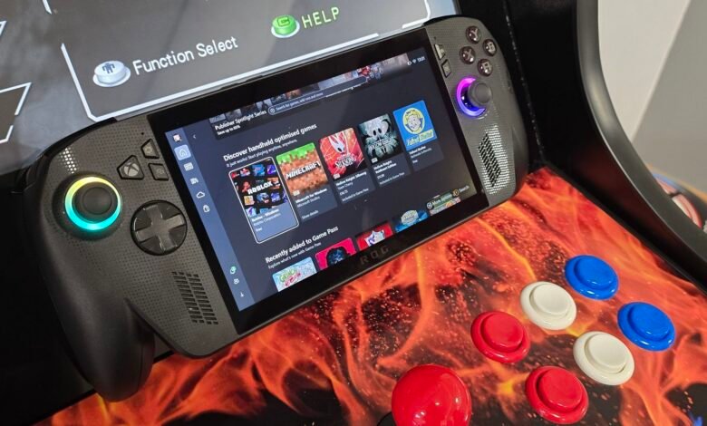 Close-up of a handheld gaming PC displaying a game library, with arcade controls in the foreground.