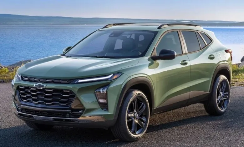Green Chevrolet Trax SUV parked on a road with a lake and hills in the background.