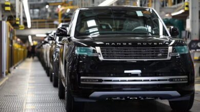 Black Range Rover vehicles lined up on an assembly line in a factory.