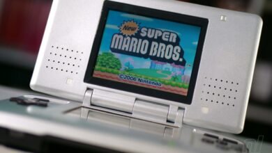 Silver Nintendo DS Lite displaying the title screen for New Super Mario Bros.