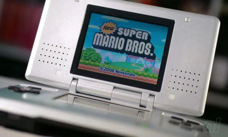 Silver Nintendo DS Lite displaying the title screen for New Super Mario Bros.