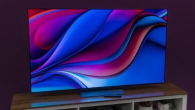 A large OLED television displaying a vibrant abstract wallpaper with flowing blue and magenta waves.