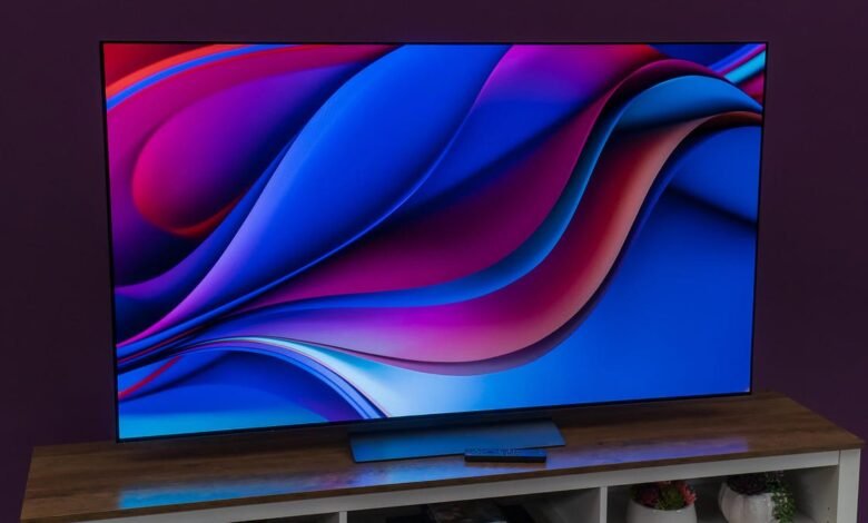 A large OLED television displaying a vibrant abstract wallpaper with flowing blue and magenta waves.