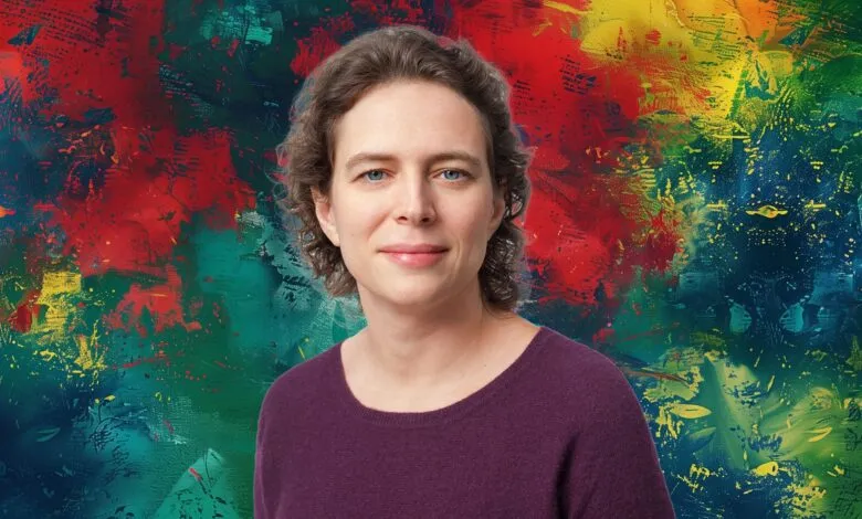 Liz Reid, a woman with short curly brown hair and blue eyes, smiles at the camera.