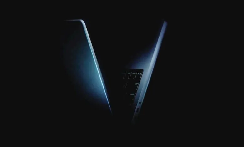 Close-up of a sleek, modern laptop with a glowing blue edge, partially open in darkness.