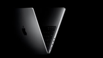 Close-up of a silver MacBook Pro with the Apple logo illuminated against a dark background.