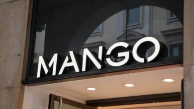 Close-up of the illuminated MANGO store sign above an entrance.