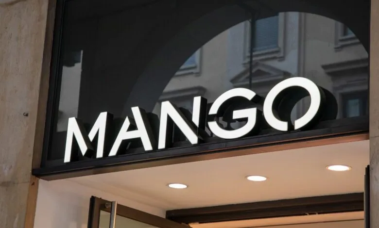 Close-up of the illuminated MANGO store sign above an entrance.