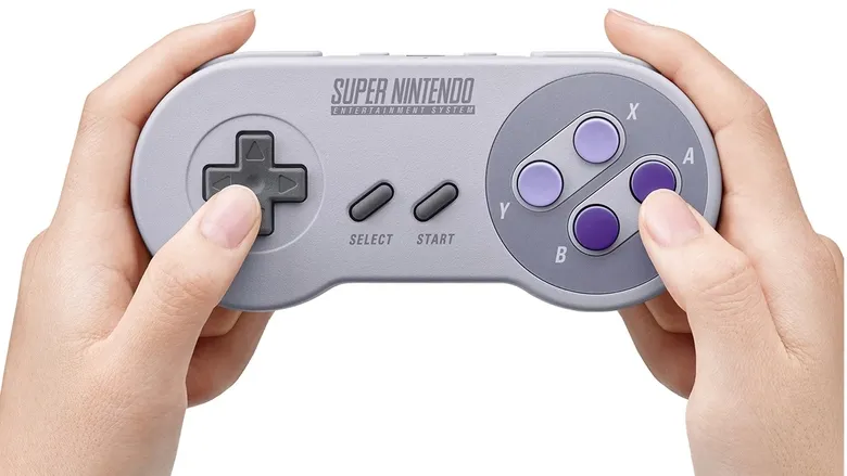 Hands holding a Super Nintendo Entertainment System controller, fingers poised to play.