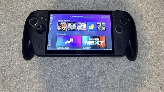 Black handheld gaming device with a vibrant purple interface displaying game tiles.