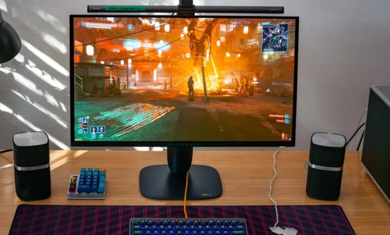 A gaming setup featuring an Alienware monitor displaying a video game, keyboard, mouse, and speakers.